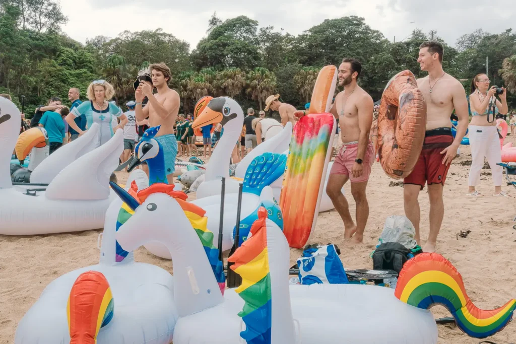 Participants preparing colourful unicorn, swan and peacock inflatables on Shelly Beach