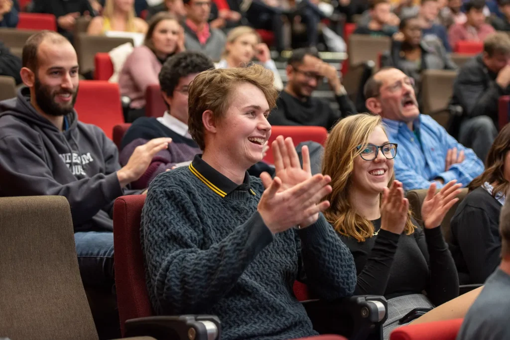 Conference audience smiling and applauding during a presentation