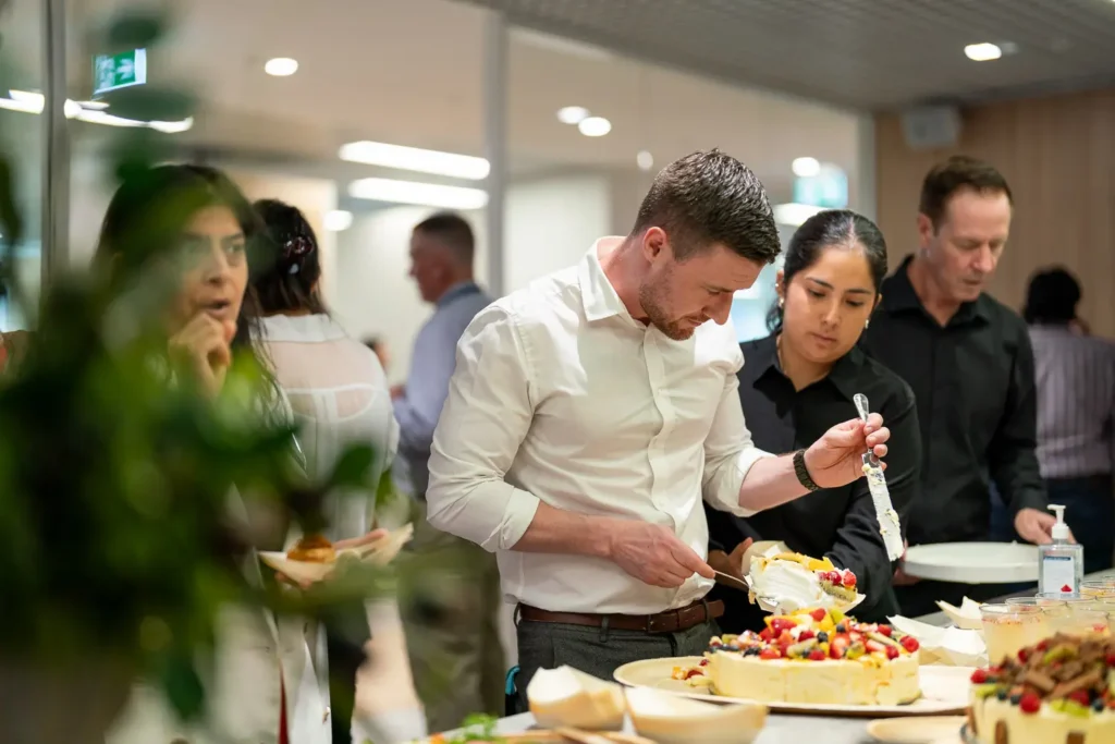 Guests serving cake and desserts during a catered corporate celebration