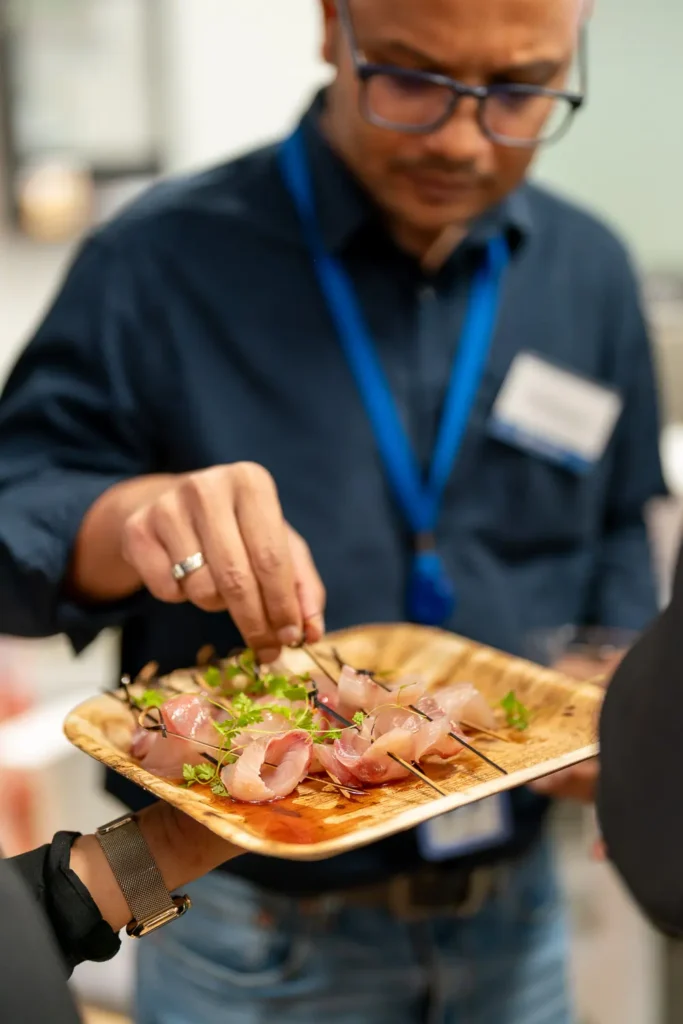 Guest choosing fresh canapés from a serving platter at a corporate networking event
