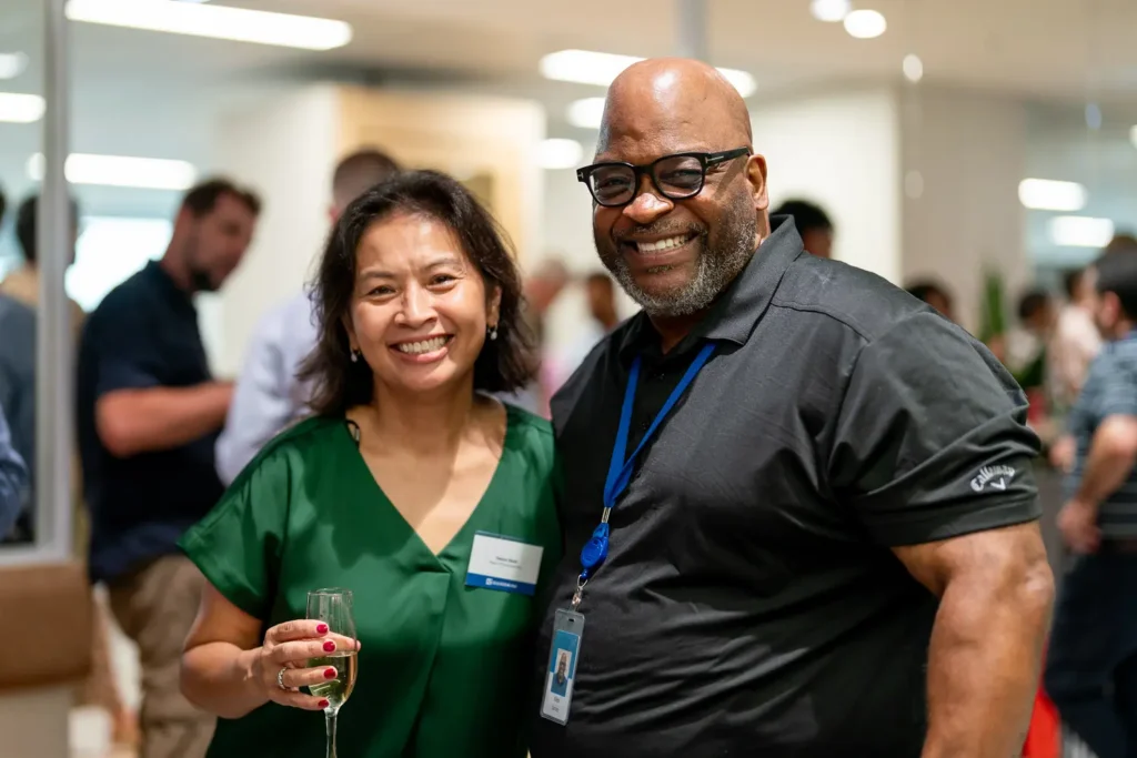 Two guests smiling together at a lively corporate networking event
