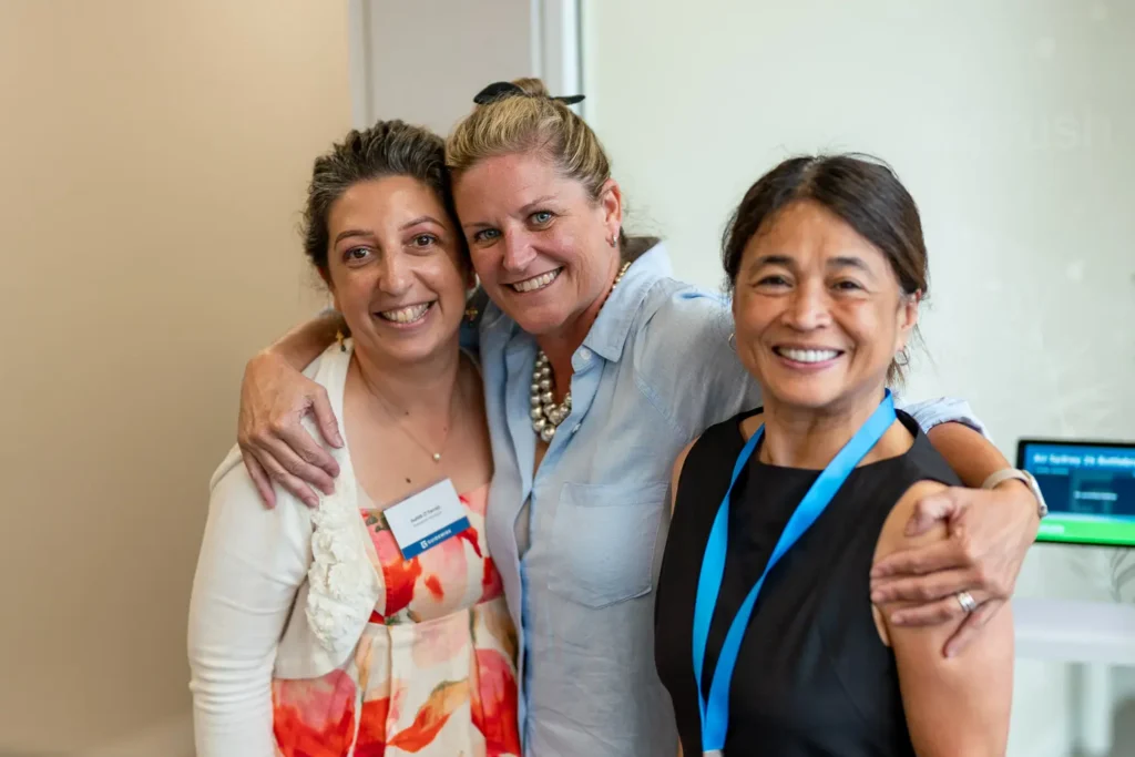 Three colleagues smiling together during an office celebration