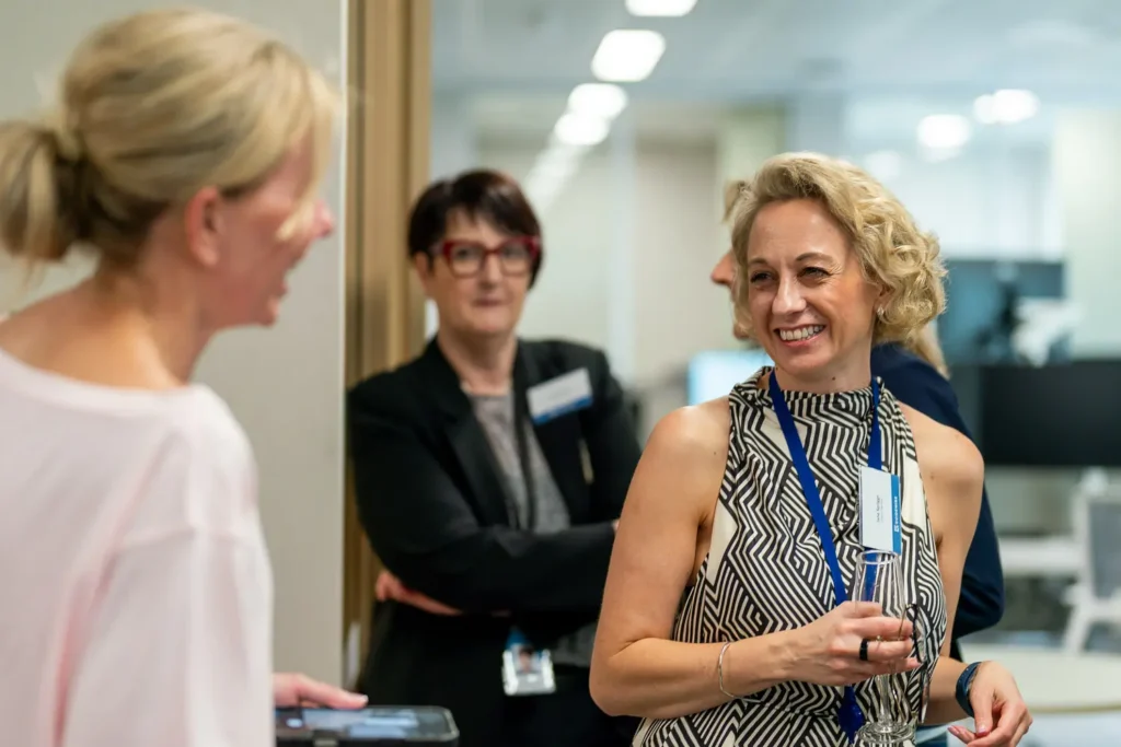 Professionals chatting and smiling during a relaxed corporate networking event
