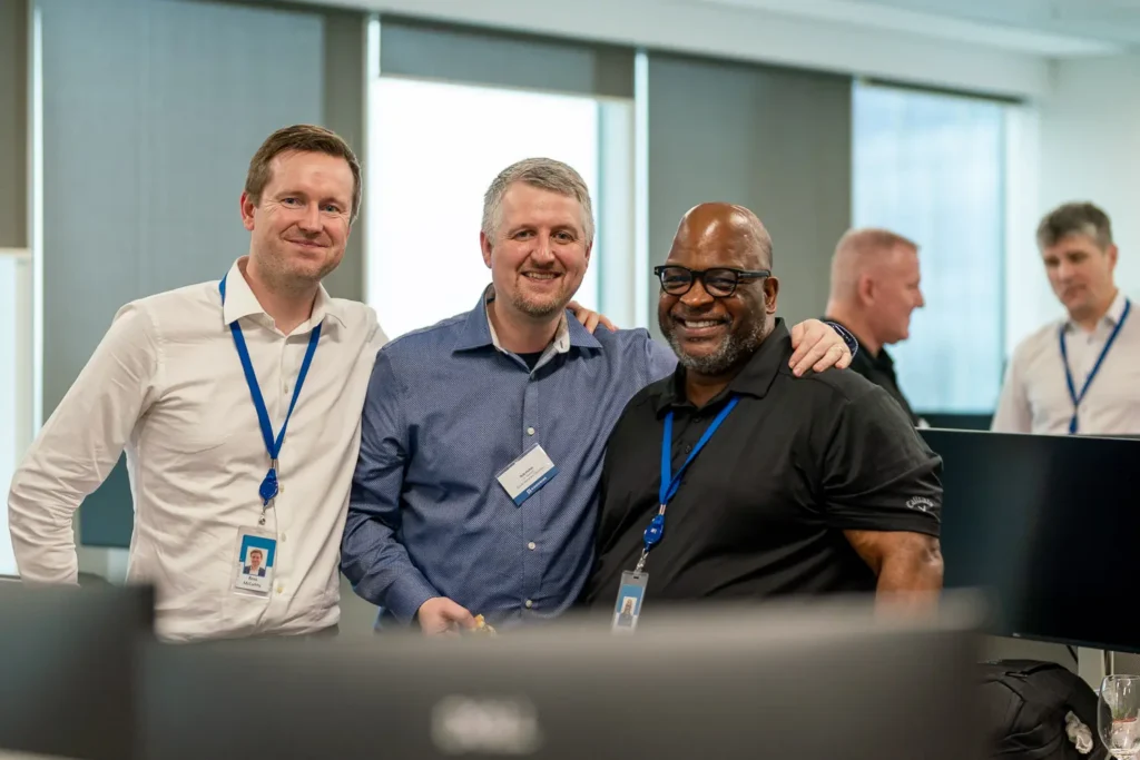 Three colleagues smiling together during a corporate office event