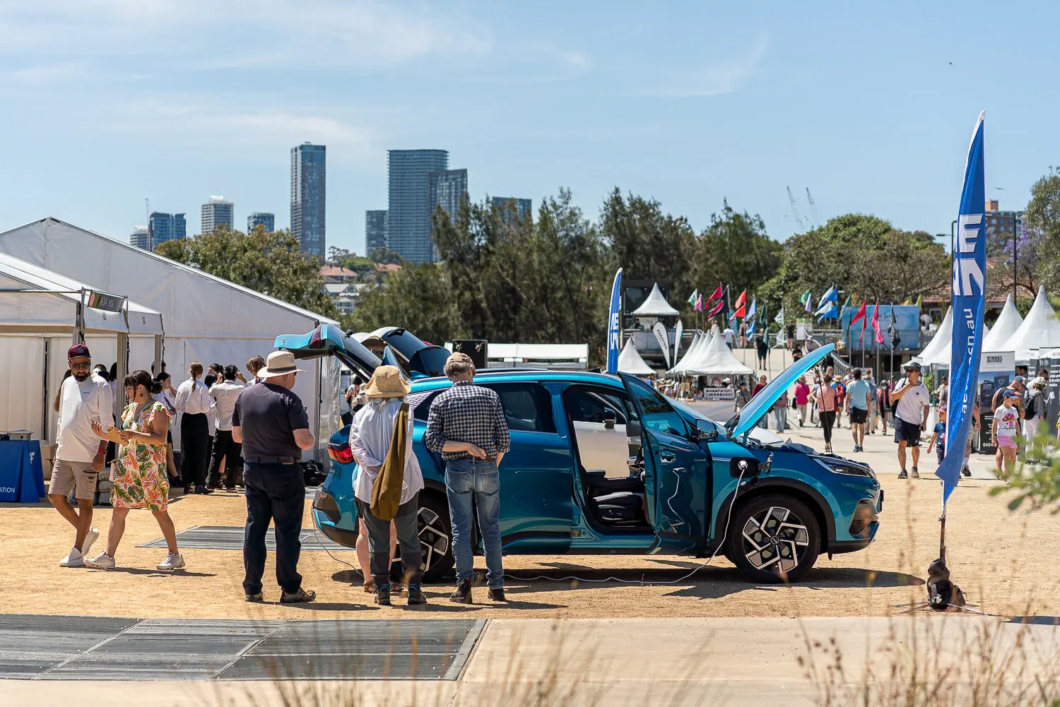 Electric vehicle on display with doors open at an outdoor sustainability festival