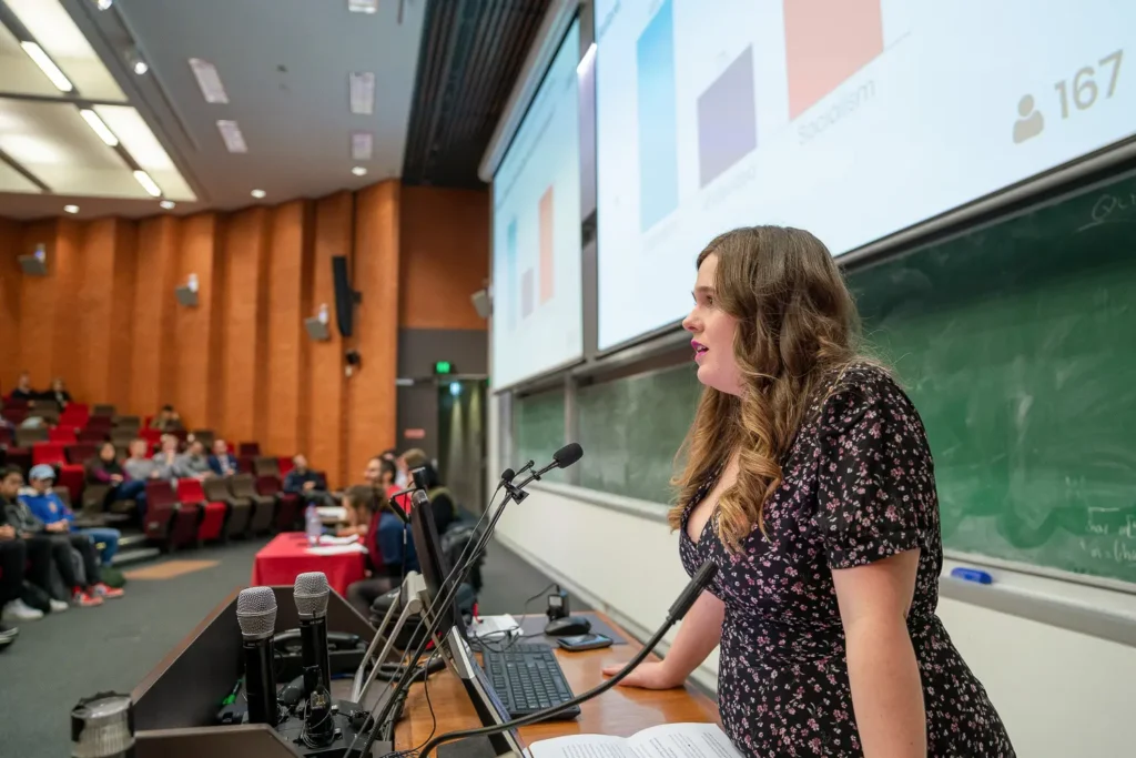 Female speaker addressing attendees from the front of a lecture theatre