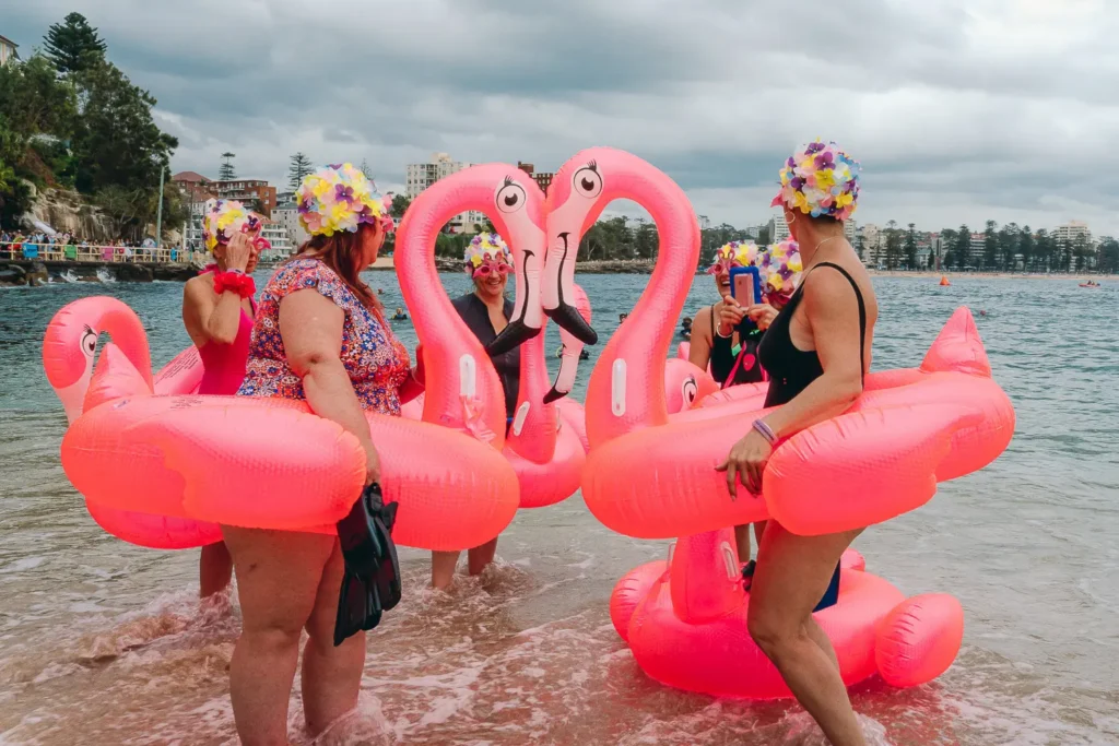 Group of participants with bright pink flamingo floats at the Manly Inflatable Boat Race