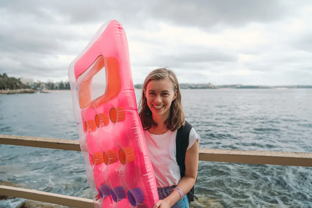 Smiling participant carrying a bright pink inflatable to the Manly Inflatable Boat Race