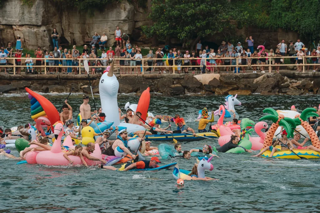 Crowded inflatable boat race with unicorns, flamingos and colourful floats at Manly