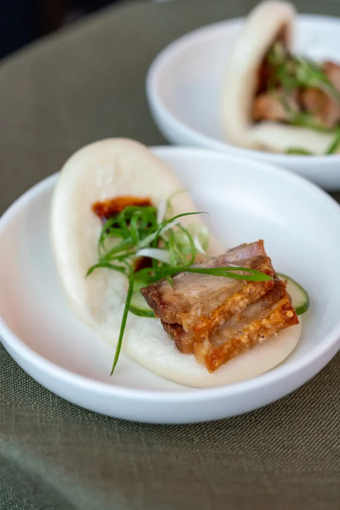 Steamed bao bun filled with crispy pork, cucumber and fresh herbs