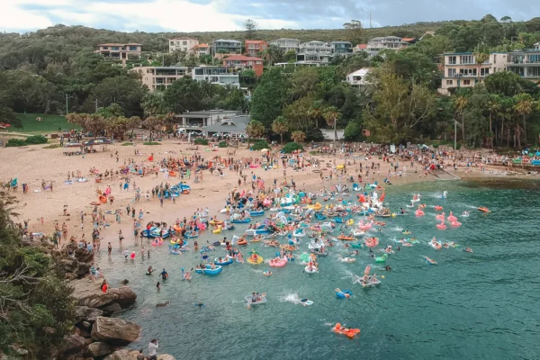 Aerial view of crowds and colourful inflatables entering the water at Shelly Beach in Manly
