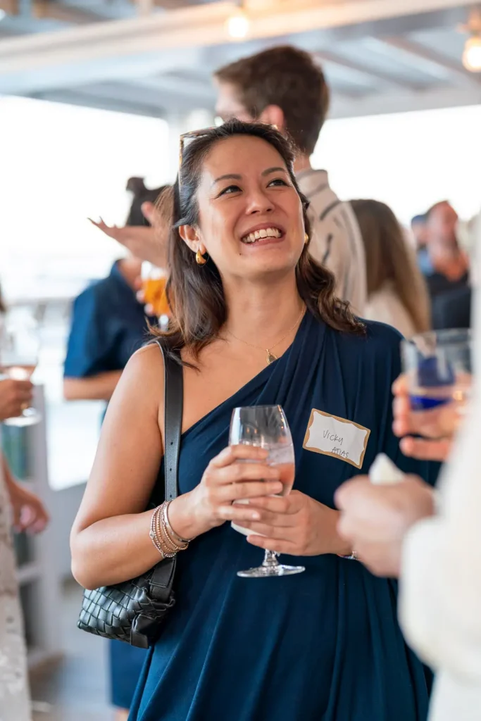 Smiling guest holding a drink while chatting at a networking event