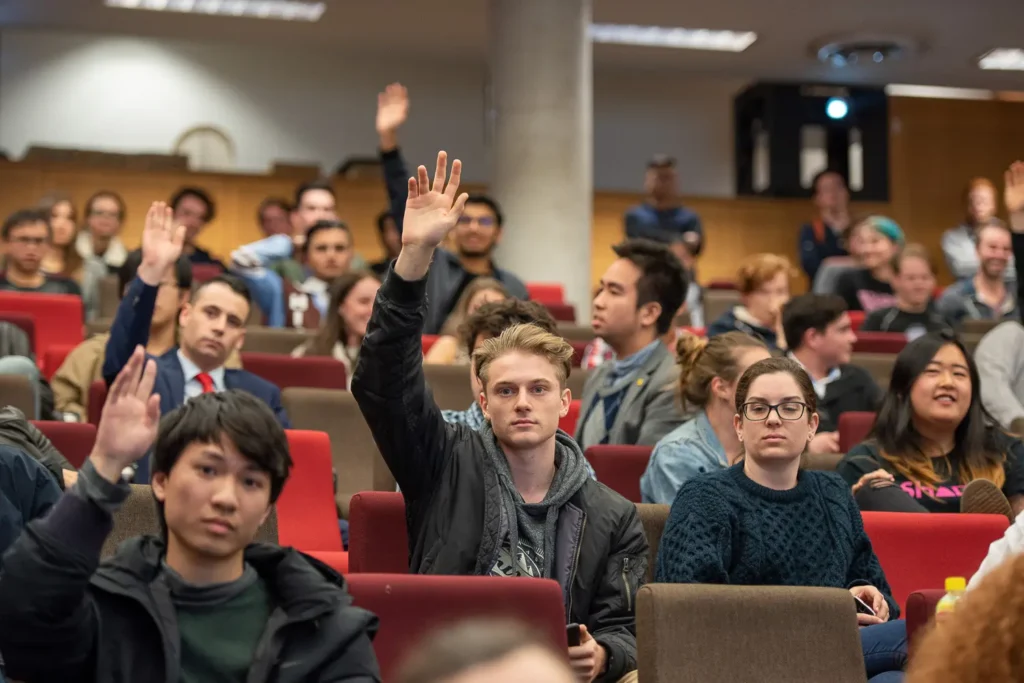 Students raising their hands during the University of Sydney debate