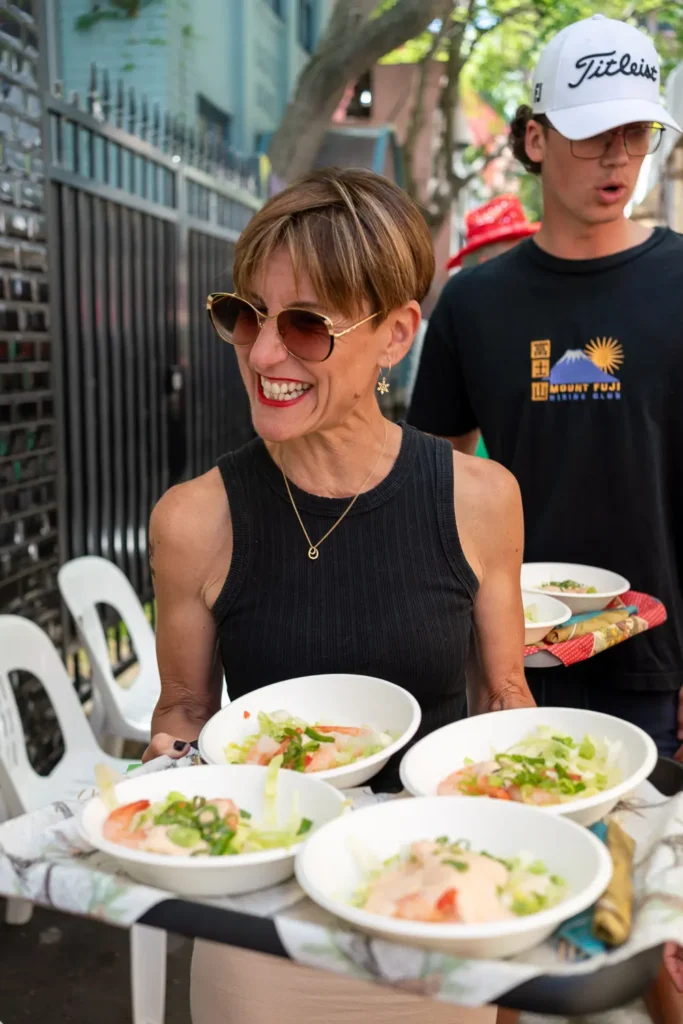 Smiling volunteer carrying bowls of fresh food at the Wayside Chapel Christmas lunch