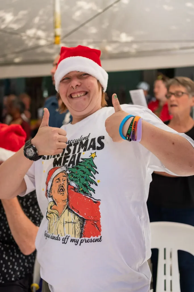 Smiling guest in a Santa hat giving two thumbs up at the Wayside Chapel Christmas celebration