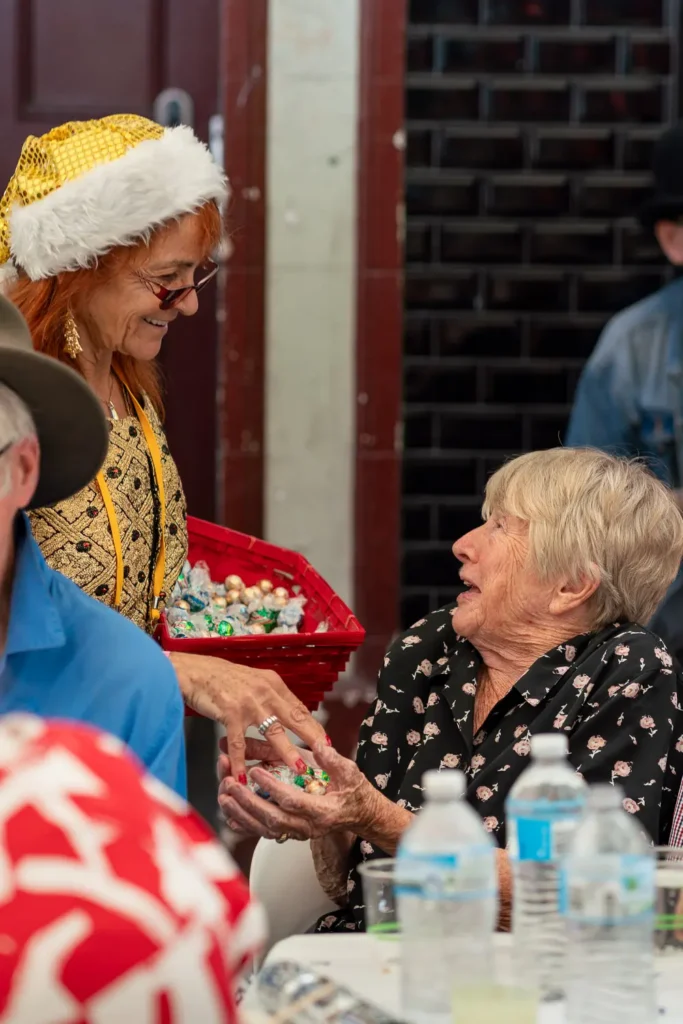 Volunteer handing Christmas treats to an older guest at the Wayside Chapel celebration
