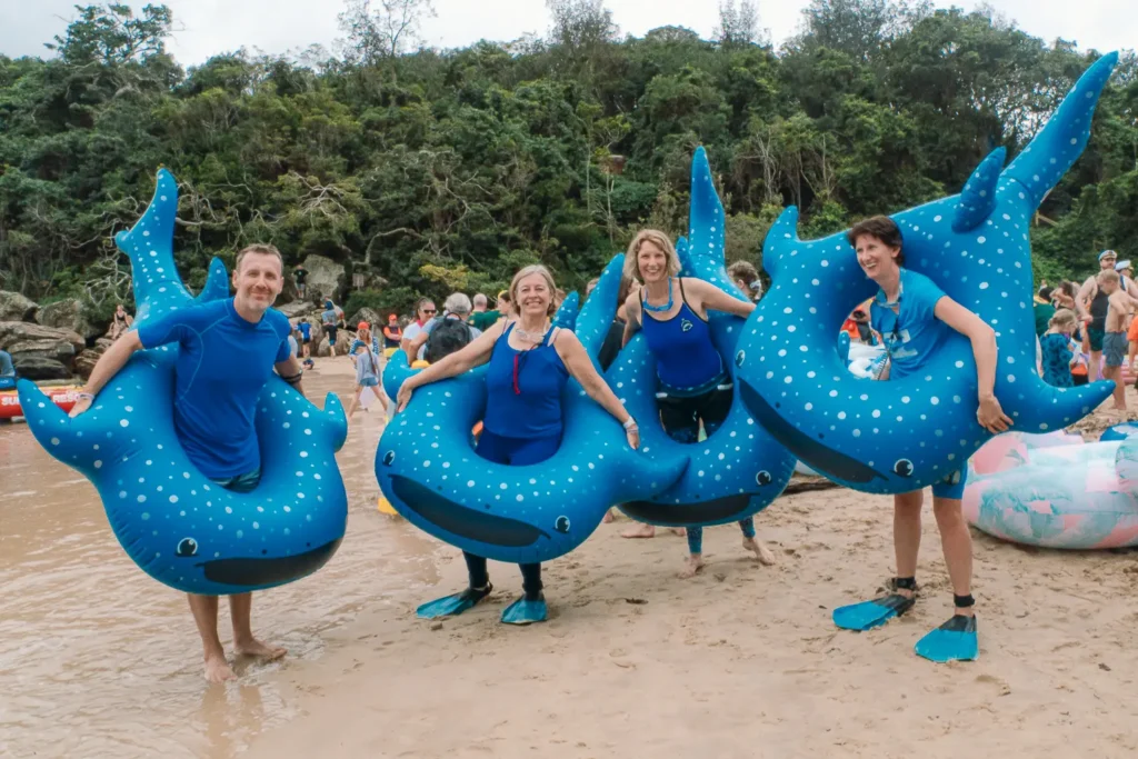 Team posing with blue whale shark inflatables at the Shelly Beach inflatable race