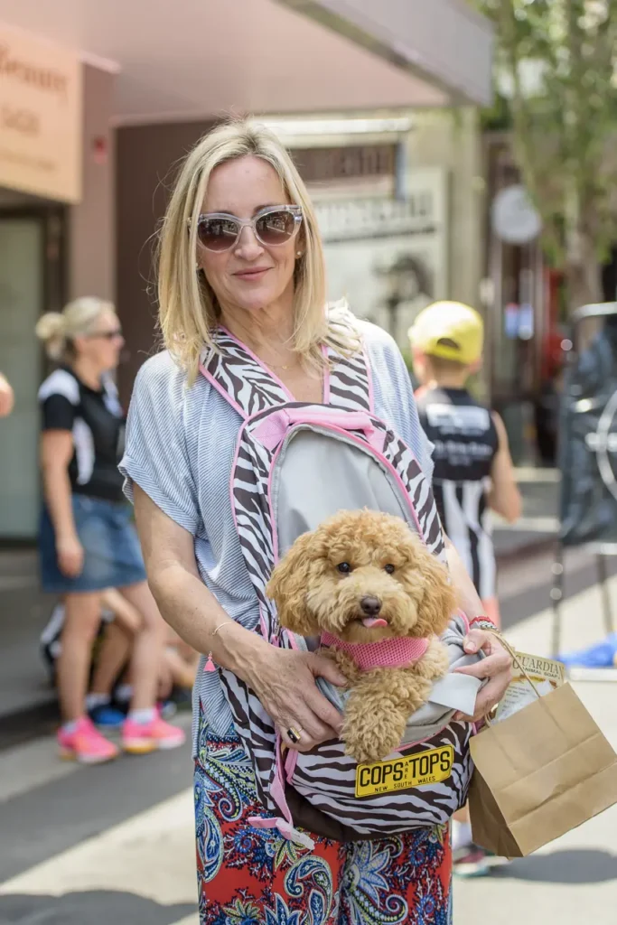 Woman smiling with her small dog in a front carrier during the dog-friendly Glebe Street Fair Sydney
