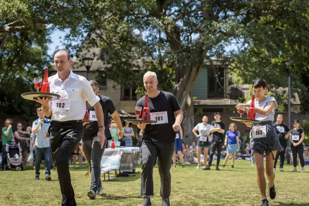 Competitors balancing trays of drinks during the Greatest Waiter Race at Glebe Street Fair Sydney