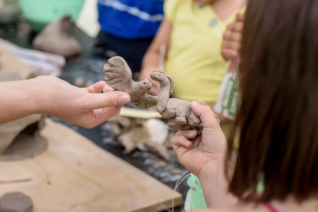 Close-up of children's hands creating clay animal sculptures during a creative workshop at Glebe Street Fair Sydney