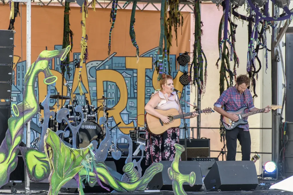 Female singer and guitarist performing live on a colourful festival stage at Glebe Street Fair Sydney