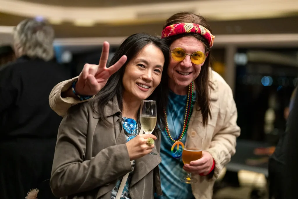 Guests in retro hippie costumes posing with drinks at a Sydney corporate event