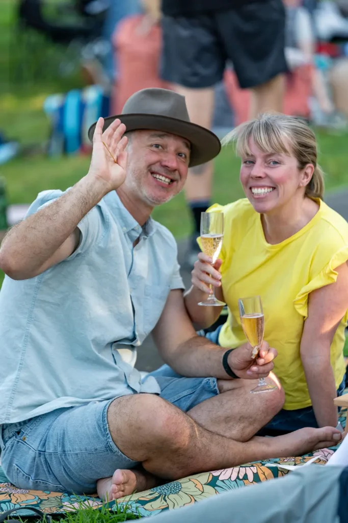 Smiling couple enjoying drinks on a picnic blanket at North Sydney Sunset Series 2022