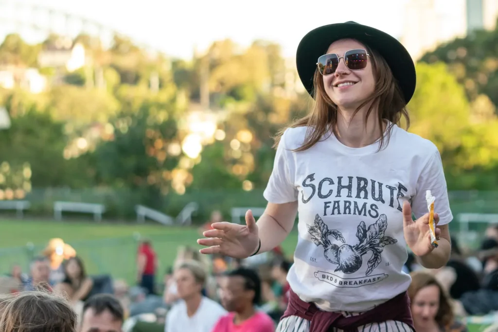 Smiling woman in a black hat dancing in the afternoon sunshine at North Sydney Sunset Series