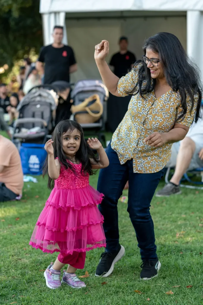 Woman and young girl dancing together on the grass at Sunset Series 2022