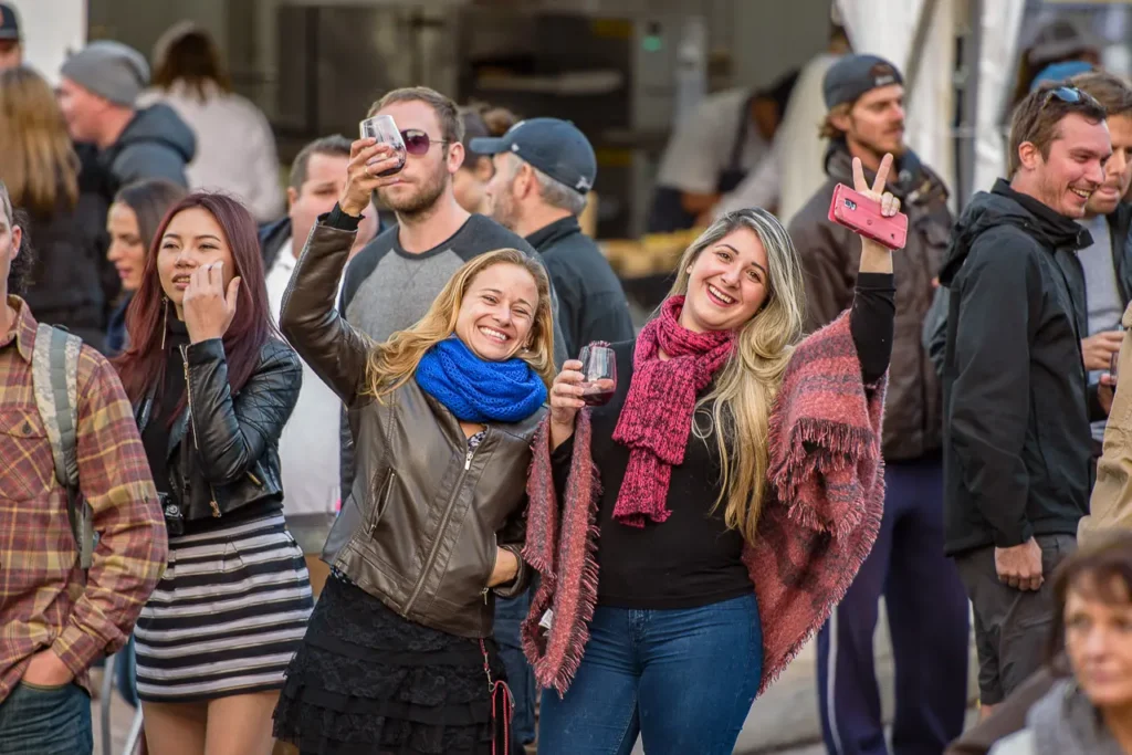 Friends celebrating with drinks in the crowd at Taste of Manly