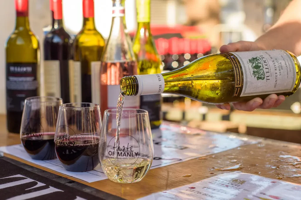 White wine being poured into a Taste of Manly glass at a festival wine stall