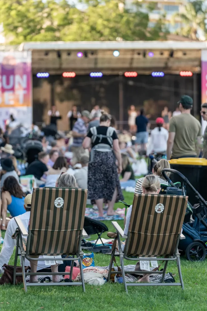 Concertgoers relaxing in deckchairs while watching live music at Waverton Park
